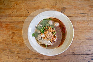 Rice noodle in spicy soup with pork ball, vegetable and pork serving on wooden desk in canteen