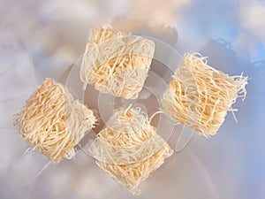 Rice noodles for Pad Thai, uncooked (raw), on blue background