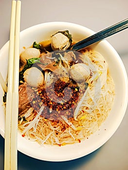 Rice noodles with pork balls in white bowl on table