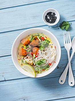 Rice noodles with roast pumpkin, cauliflower and curry sauce on blue wooden background