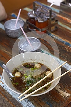 Rice noodles soup with meat ball in a bowl eating by chopsticks, Asian food, Thai style, Angle view. Cold water