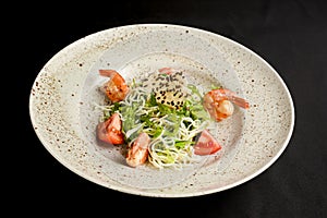 Rice noodles with tomatoes, fresh lettuce saladn and sesame seeds. Asian noodles salad on a plate