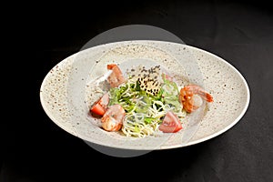 Rice noodles with tomatoes, fresh lettuce saladn and sesame seeds. Asian noodles salad on a plate