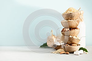 Rice, oat, almond, hazelnut and soy beans in natural palm leaf bowls and milk bottles on the table, Ingredients for making Dairy