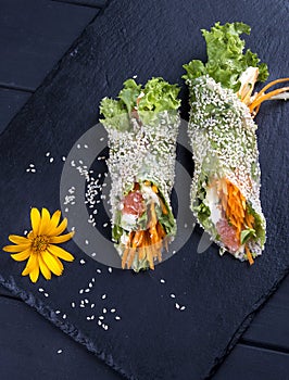 Rice paper rolls with sesame, vegetables and tuna. Asian dish. On a dark stone. Healthy food