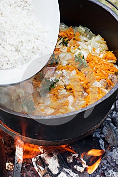 Rice pilau is cooking in the pot on the fire, asian dish, rice pilau, on the fire