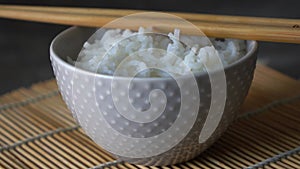 Rice in a porcelain bowl, with Japanese chopsticks, soy sauce, served on a gray stone table Close up