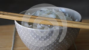 Rice in a porcelain bowl, with Japanese chopsticks, soy sauce, served on a gray stone table Close up