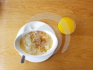 Rice with Pork boiled breakfast with the Orange Juice and Drinking Water on woodeb table. & x28;Asia traditional food