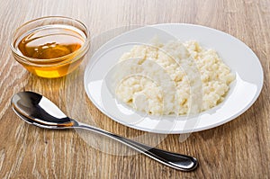 Rice porridge with milk in plate, bowl with honey