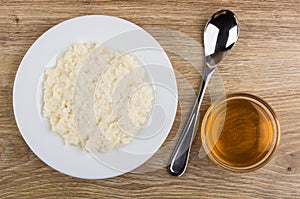 Rice porridge with milk in plate, bowl with honey, spoon