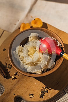 Rice porridge in a pottery with butter. Rustic style with a wooden spoon. Milk porridge on a wooden table