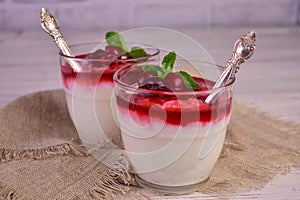 Rice pudding with cherry jam on a white wooden background.