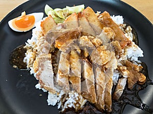 Rice with Roasted pork and Deep fried pork on top, serve in black dish.