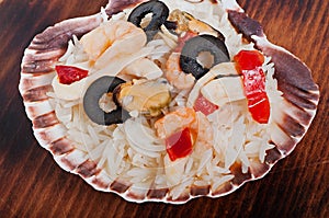 Rice in the shell, decorated with seafood, shrimps, mussels, squid rings and olives.