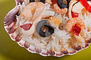 Rice in the shell, decorated with seafood, shrimps, mussels, squid rings and olives.