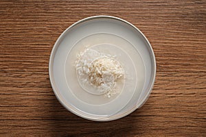 Rice soaked in water on wooden table, top view