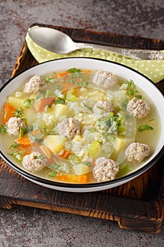 Rice soup with meatballs and vegetables close-up in a bowl. Vertical