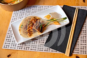 Rice in spicy sauce on sesame pancake, pickled vegetable and fruit on rectangle plate, towel, chopsticks and bowl