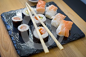 Rice, Sushi on a wooden table on black slate plate with soy sauce and chopsticks