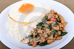 Rice topped with stir-fried chicken, basil and fried egg, fried stir basil with minced chicken on brown background