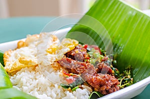 Rice topped with stir-fried pork, basil leaves and chili served