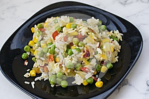 Rice with vegetables in a black plate photo