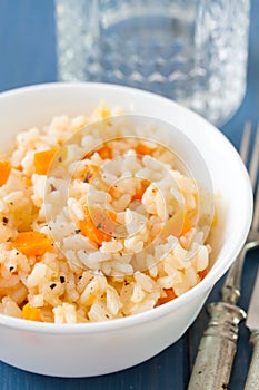 Rice with vegetables in white bowl with glass