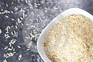 Rice in a white plate is on a dark table