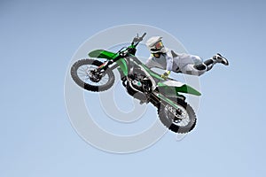 Ricer in a white protective uniform and helmet shares a stunt in the air on a motorcycle.