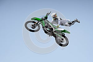 Ricer in a white protective uniform and helmet shares a stunt in the air on a motorcycle. photo