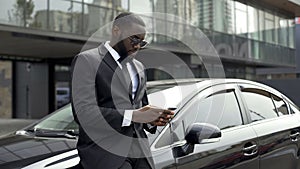Rich Afro-American man waiting for partners near office building to do business photo