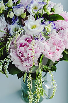 Rich bunch of pink peonies peony and lilac eustoma roses flowers in glass vase on white background. Rustic style, still life.