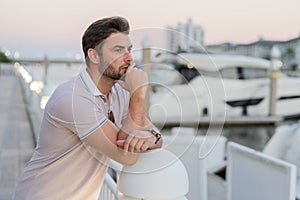 Rich business man dreaming and thinking near the yacht. Handsome confident stylish hipster model posing outside. Sexy