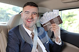 Rich businessman holding full wallet in taxi