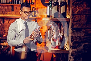 Rich businessman owning bar looking at bottles of alcohol