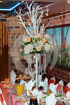 Rich centrepieces made of rose bouquets on tall vases stand