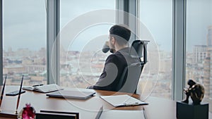 Rich ceo drinking coffee sitting office chair looking window cityscape close up.