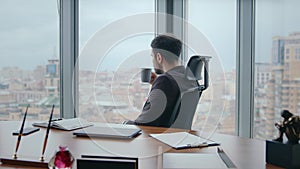 Rich ceo drinking coffee sitting office chair looking window cityscape close up.