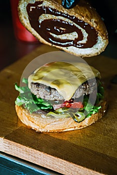Rich cheeseburger in making, fluffy buns, beef burger meat, lettuce, bbq sauce and cheese