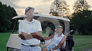 Rich couple enjoy golf evening on fairway. Family golfers relax summer holiday.