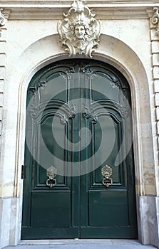 The rich decor decorates an entrance door of the old building of traditional architecture of in downtown, Paris.