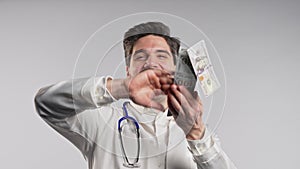 Rich doctor man scatters money. Handsome medical health care worker in white coat overspend USD dollars banknotes.