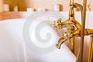 Rich gold faucet and white bath in the bathroom