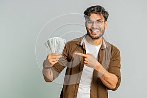 Rich happy Indian man winner waving money dollar cash like a fan, big income wealth success business
