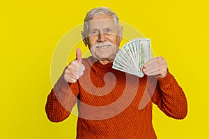 Rich happy senior man winner waving money dollar cash like a fan, big income wealth success business