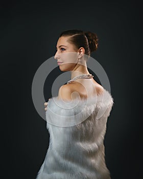 Rich lifestyle. Beautiful sexual woman wearing jewelery and white fur vest. Beauty, fashion