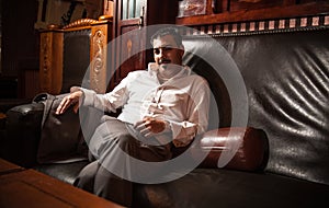Rich man sitting on vintage leather sofa