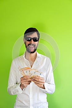 rich man with many euro banknotes in his hands sticks out his tongue happily. green copy space