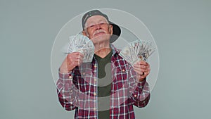Rich pleased boss senior man waving money dollar cash banknotes like a fan, success business career